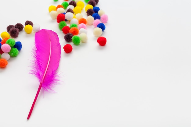 Colourful cotton balls and pink feather copy space