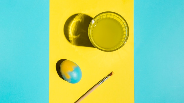 Colourful Easter egg with paint brush and glass of water 