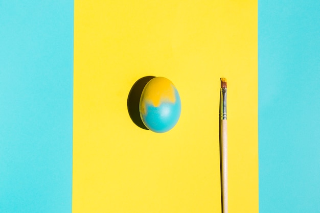 Colourful Easter egg with paint brush on table