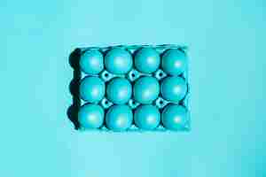 Foto gratuita uova di pasqua variopinte in scaffale sulla tavola blu