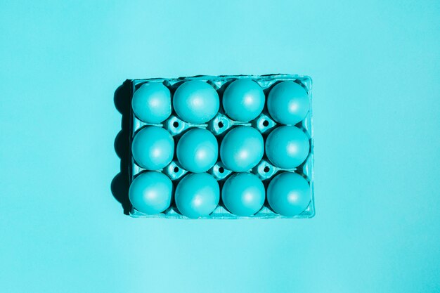 Colourful Easter eggs in rack on blue table