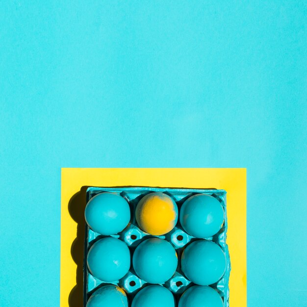 Colourful Easter eggs in rack in frame on blue table