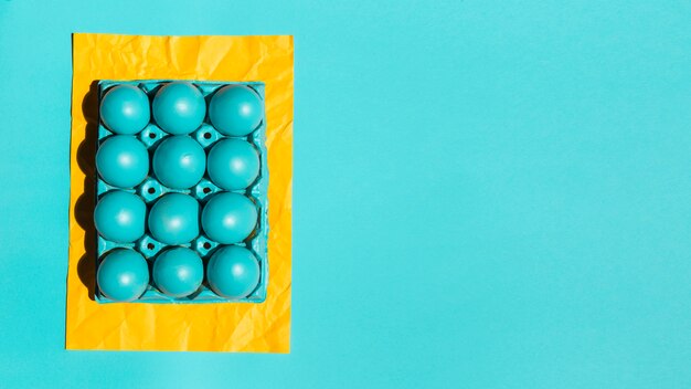 Colourful Easter eggs in rack on yellow paper on table