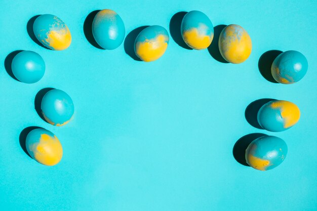 Colourful Easter eggs scattered on blue table