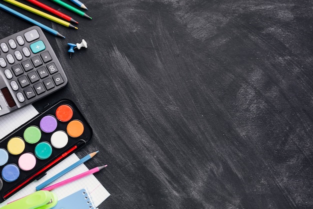 Красочные краски, калькулятор и карандаши на сером фоне