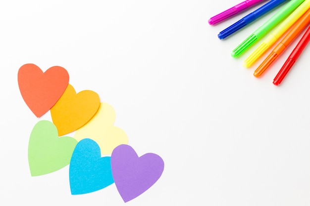 Free photo colourful pencils and paper hearts