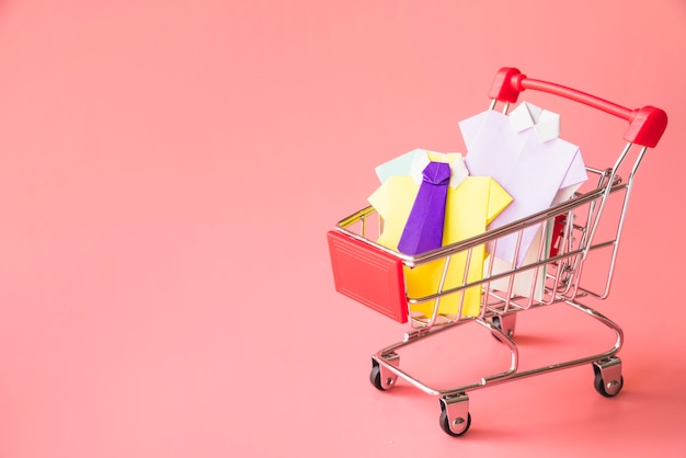 Free photo colourful toy paper shirts in shopping trolley