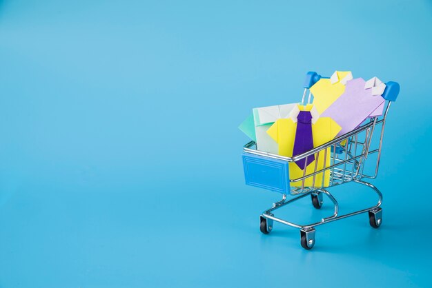 Colourful toy paper shirts in supermarket cart 