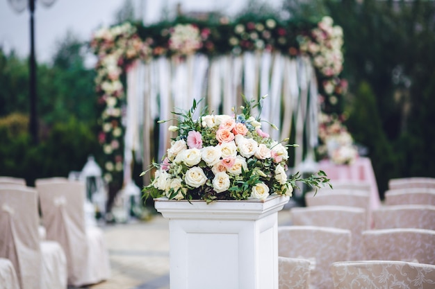 Column with rich bouquet of roses stands outside