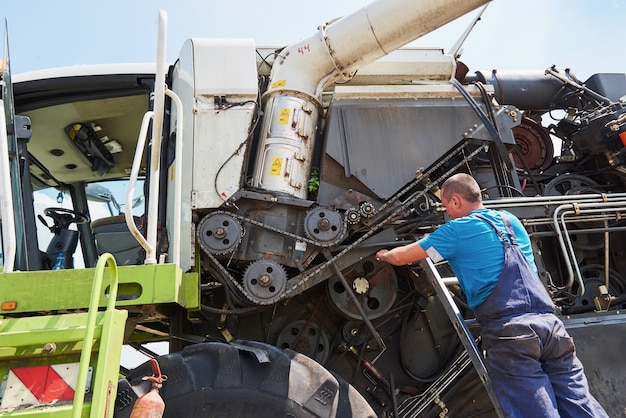 Combine machine service, mechanic repairing motor outdoors.