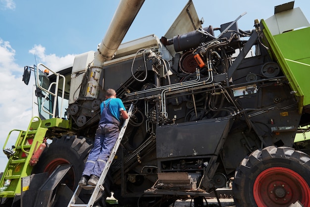 Combine machine service, mechanic repairing motor outdoors.