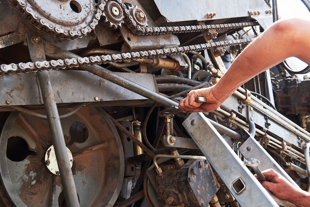 Combine machine service, mechanic repairing motor outdoors.