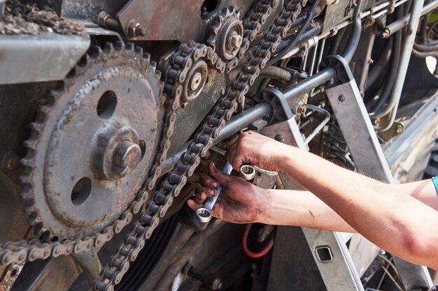 Free photo combine machine service, mechanic repairing motor outdoors.