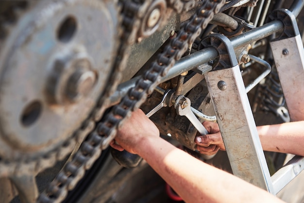 Combine machine service, mechanic repairing motor outdoors.