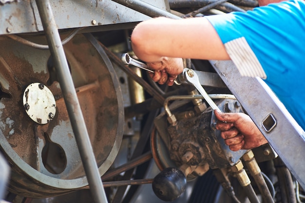 Combine machine service, mechanic repairing motor outdoors.