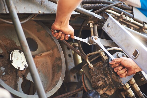 Combine machine service, mechanic repairing motor outdoors.