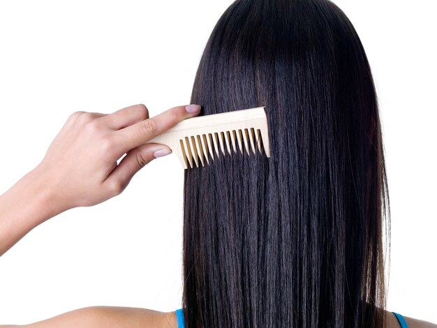 Combing healthy long straight female hair - close-up