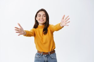 come here happy smiling woman stretch out hands to hug or welcome you reaching to hold something receiving a gift standing on white background