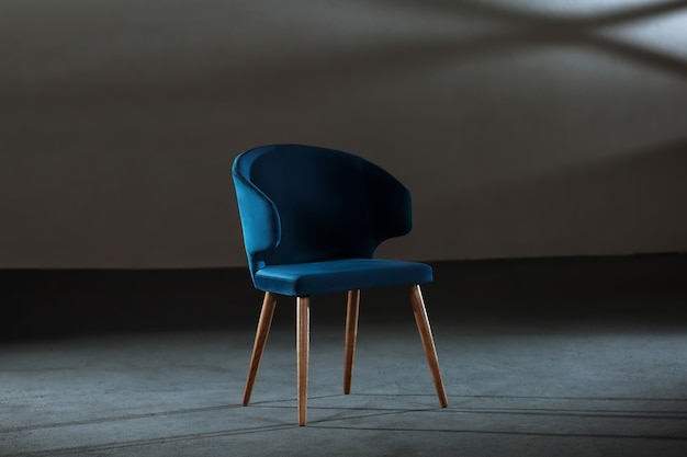 Удобное синее кресло с подлокотниками в студии с серыми стенами