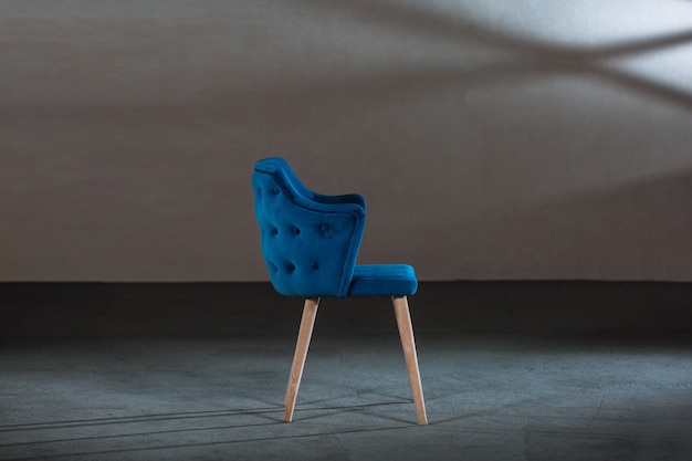 Комфортное синее кресло с подлокотниками в студии с серыми стенами