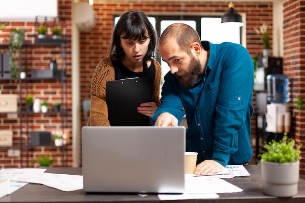 Communication team looking at management strategy using laptop analyzing business paperwork brainstorming business ideas. businesspeople working at financial project planning marketing meeting