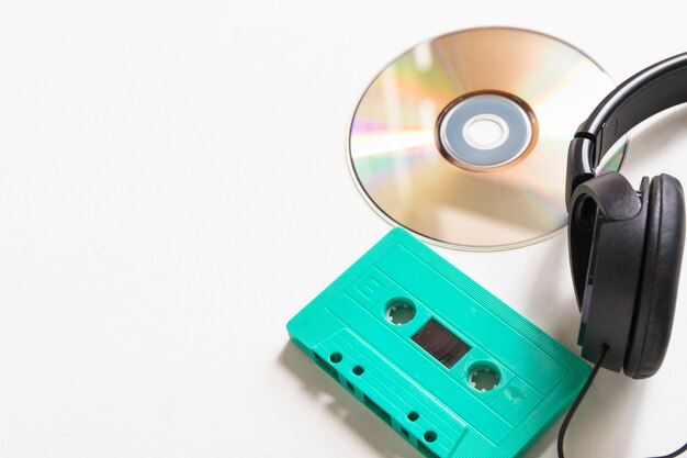 Compact disc; turquoise cassette and headphone over white background