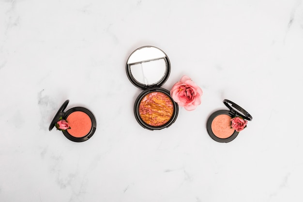 Compact face powder with rose and buds on marble textured backdrop