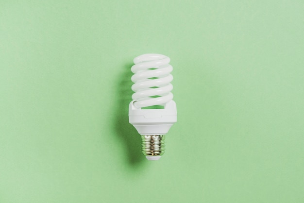 Compact fluorescent light bulb on green background
