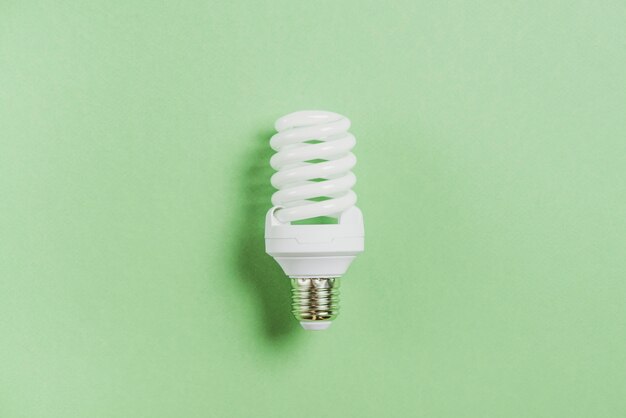 Compact fluorescent light bulb on green background