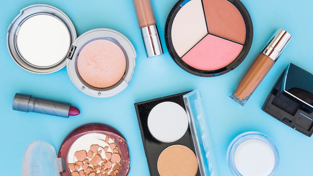 Compact powder; lipstick; foundation on blue background