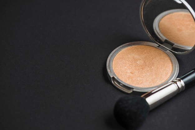 Compact powder with brush on black backdrop