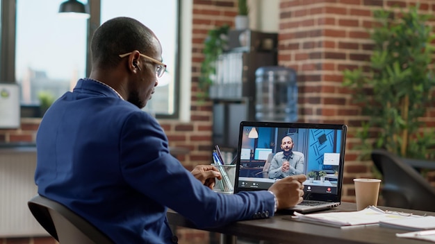 Company employee attending remote videocall meeting with man on laptop, having conversation on webcam. Talking to manager on online teleconference call, internet telework communication.