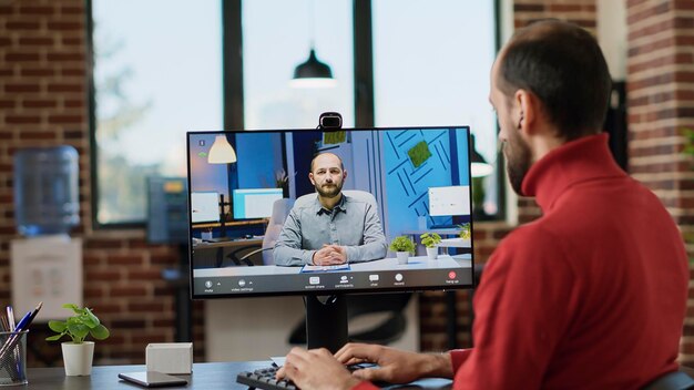 Company employee using online videocall conference to have remote conversation in office. Male worker talking to consultant on video teleconference, attending briefing meeting on computer.