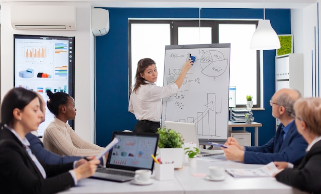 Company head standing in front of audience diverse staff members making presentation