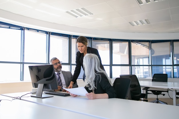 Free photo company managers reporting to female boss. businesspeople sitting at meeting table with holding paper and talking. business discussion or teamwork concept