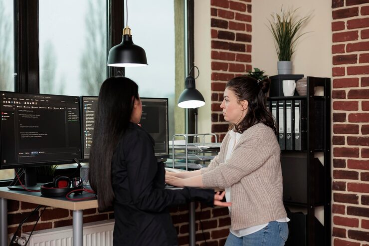 Free Photo company programmers standing near desk with multiple monitors on top of it. network developers updating firewall system through information processing using multiple layers of security.