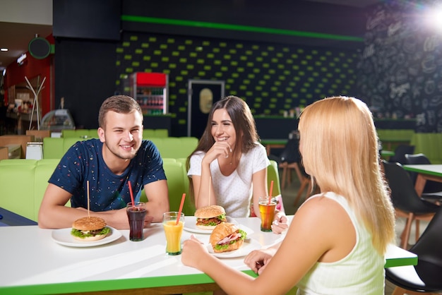 Company sitting at table in cafe and having rest