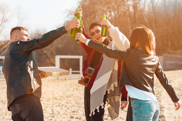 Company of smiling friends having fun with beer in open air