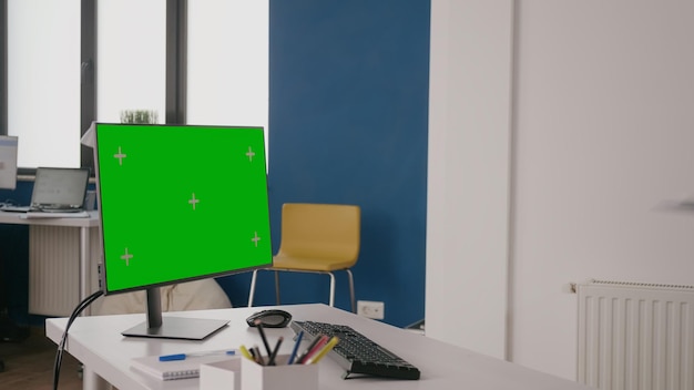 Company worker using green screen on computer at desk. Woman working with isolated mock up template and chroma key on background. Monitor with mock-up copy space on display in office.