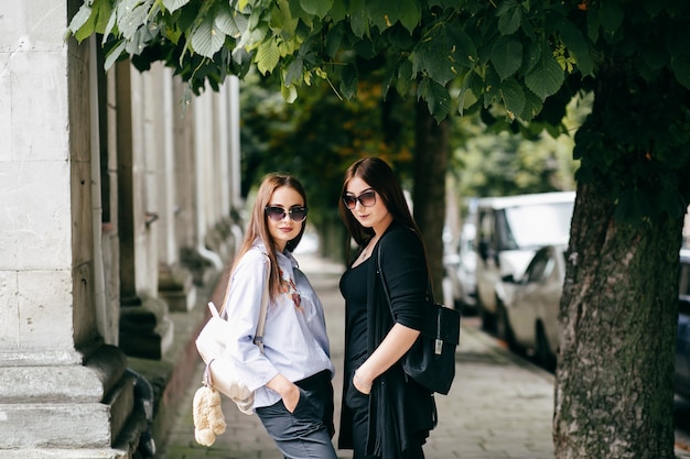 company of young friends with smartphones walking in city