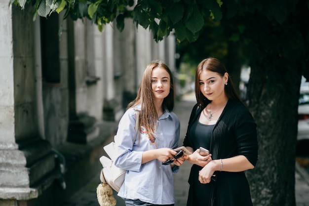 company of young friends with smartphones walking in city