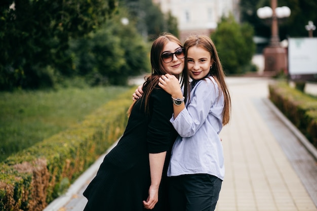 company of young friends with smartphones walking in city