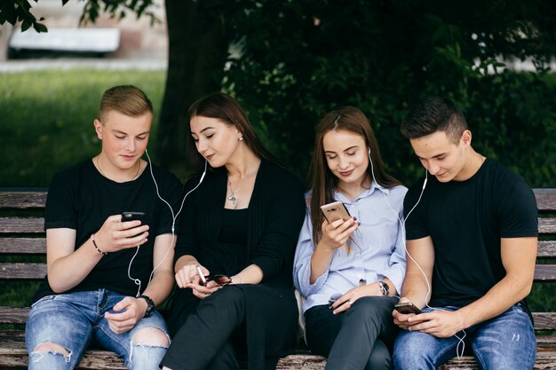 company of young friends with smartphones walking in city