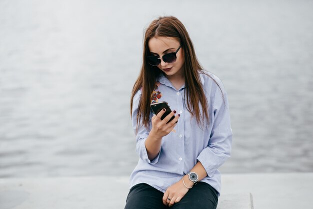 company of young friends with smartphones walking in city