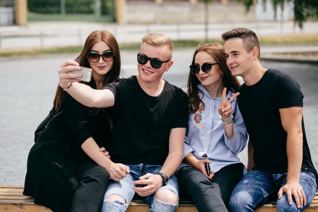 company of young friends with smartphones walking in city