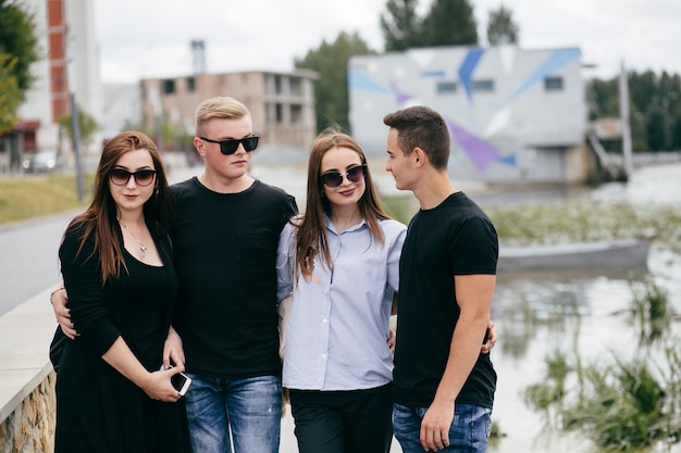 company of young friends with smartphones walking in city