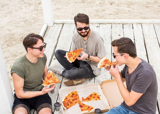 ビーチでピザを食べる若い人たちの会社