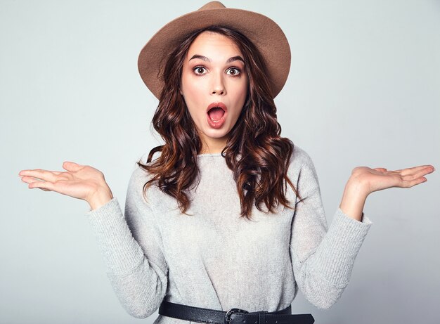 Comparison concept. Young brunette woman in casual clothes and brown hat