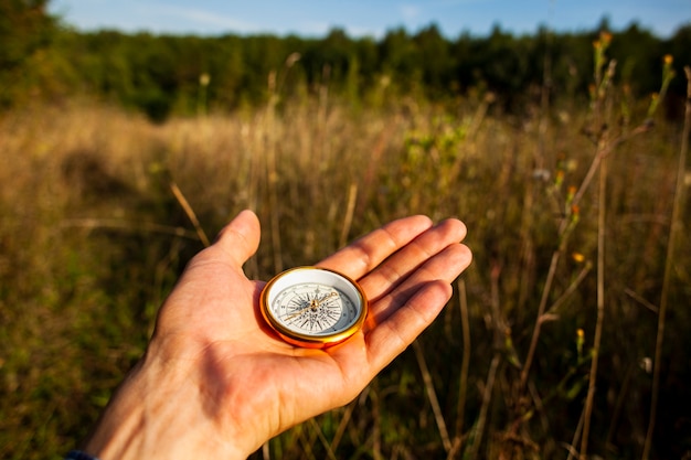 Compass held by hand and blurred background