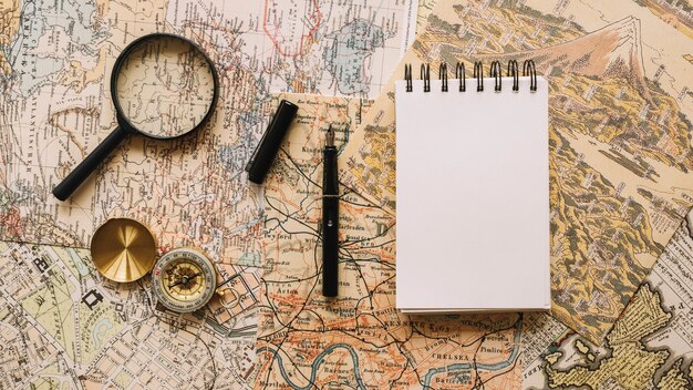 Compass and magnifying glass near notebook and pen